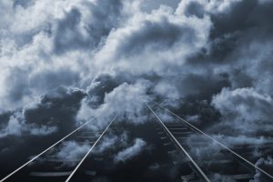 Train tracks stretching into distant cloud.